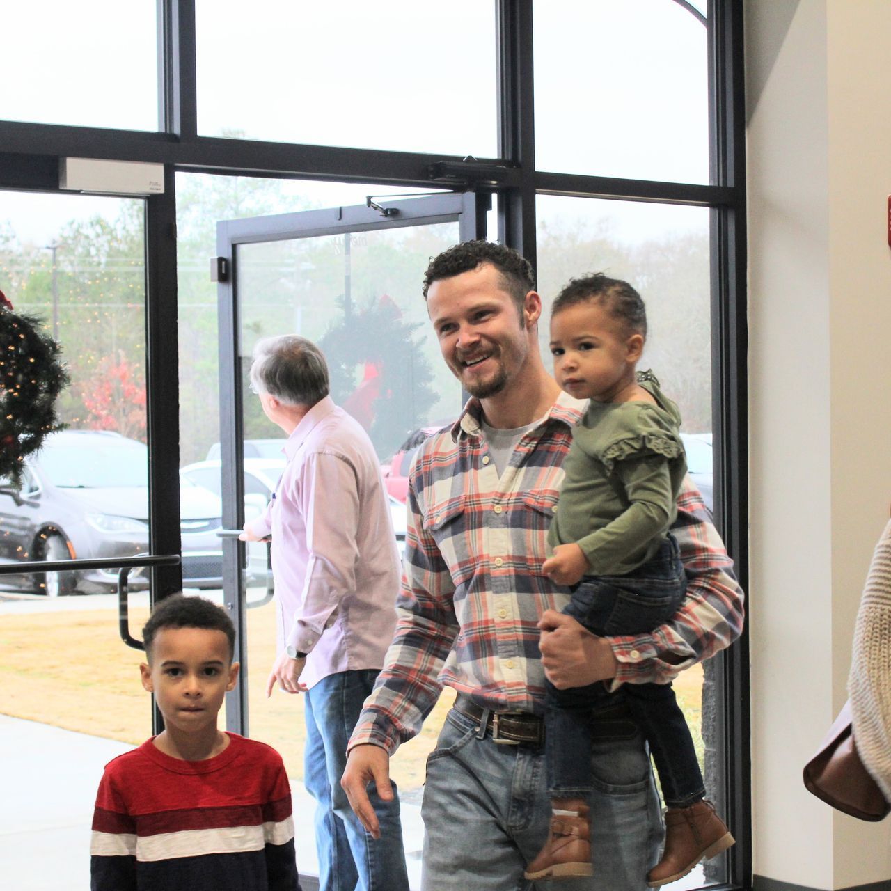 A man in a plaid shirt is holding a baby in his arms