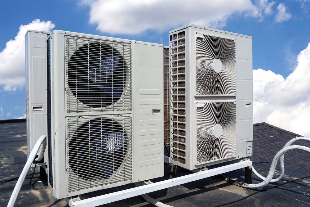 White air conditioning units on a rooftop against a blue sky with clouds. — Cooling Plus Refrigeration & Airconditioning in Ciccone, NT