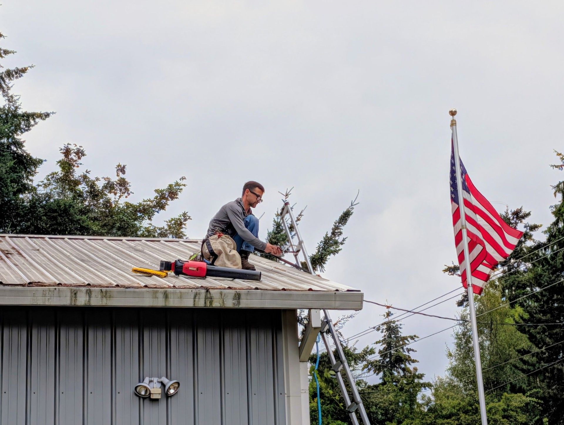 Worker on a roof near an American flag on a pole.