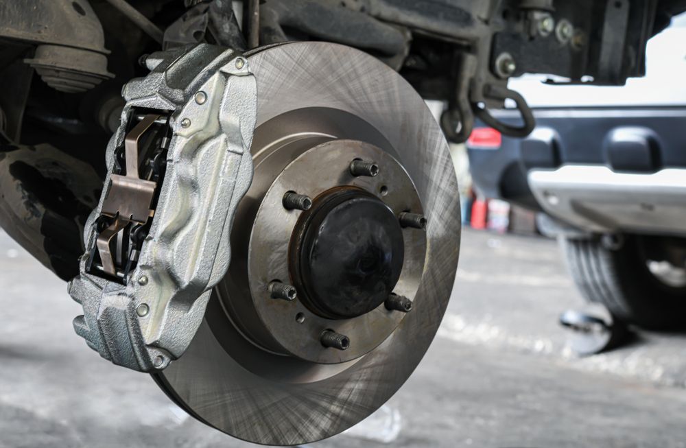 Car Brake Disc and Caliper Assembly, Silver and Black, in a Repair Shop.