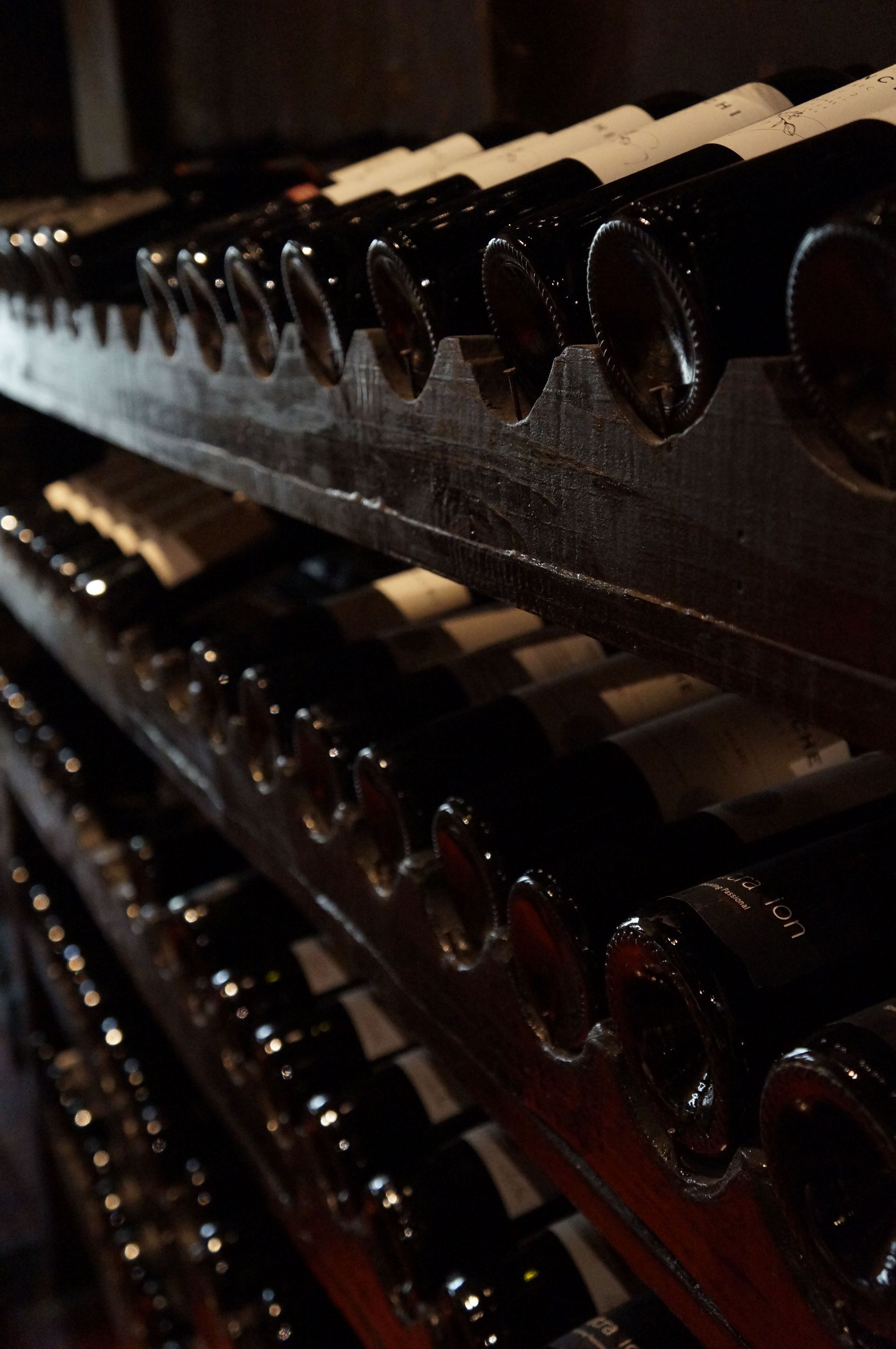 Rows of dark wine bottles stacked in a dimly lit rack
