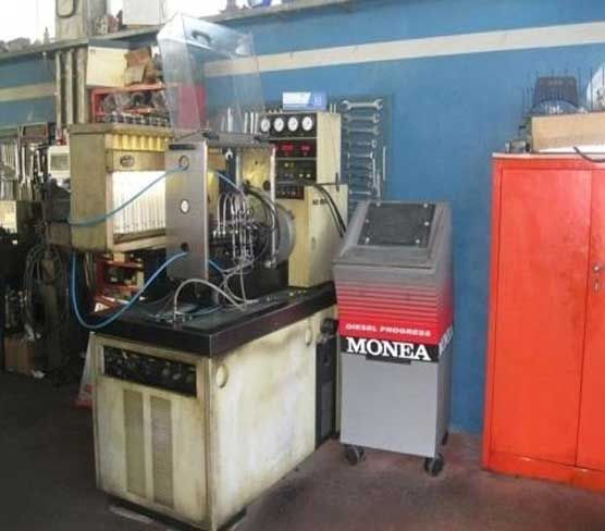 Macchinario industriale in un'officina accanto a un armadio rosso e un carrello grigio MONEA.