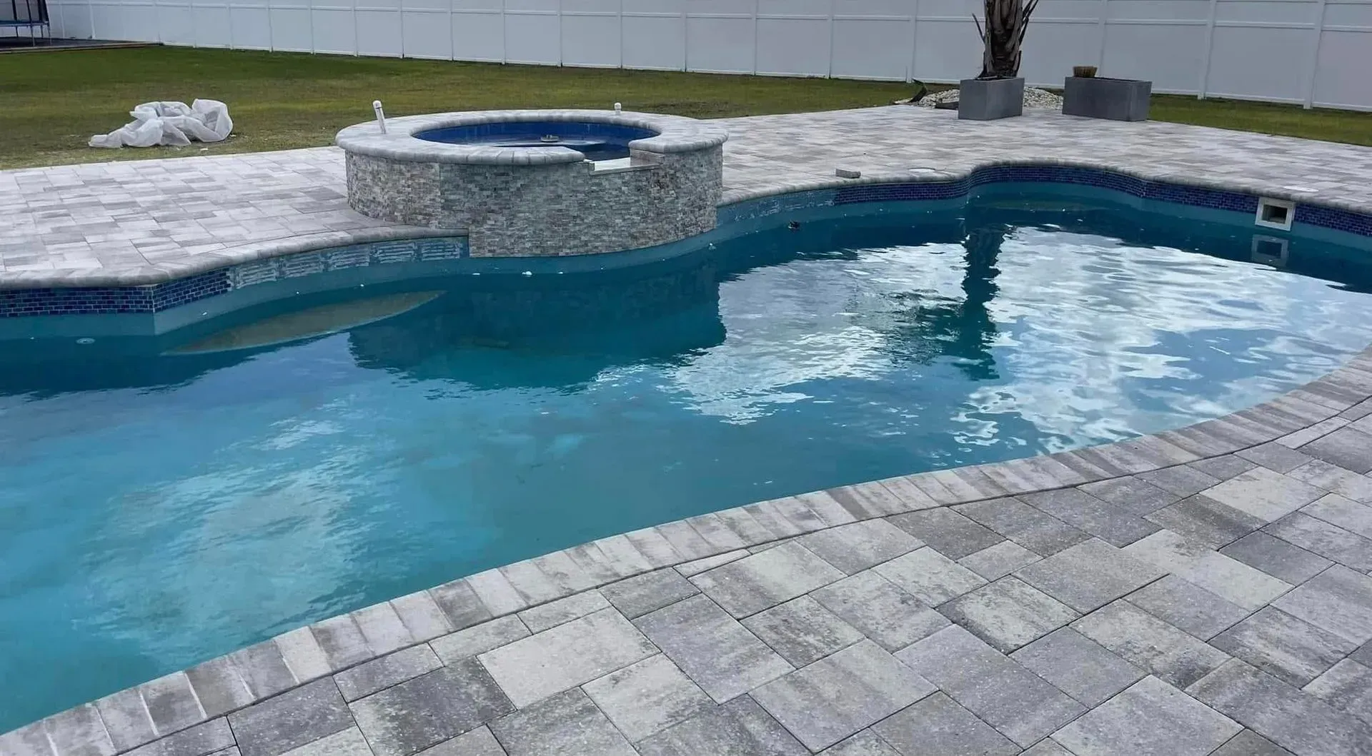 Backyard swimming pool with blue water, stone deck, and circular spa.