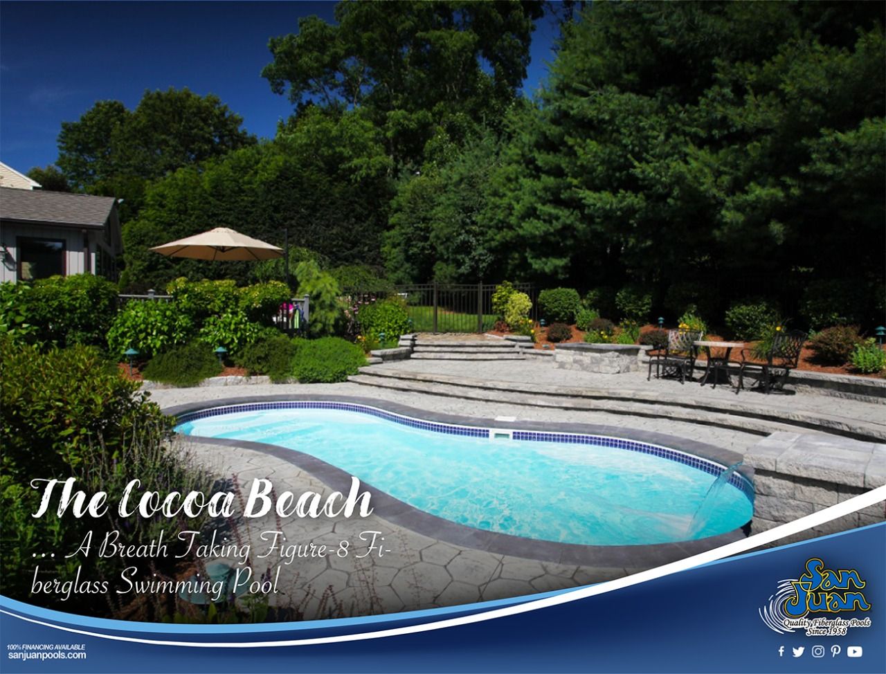 Resort pool with blue water, patio seating, and lush greenery under a sunny sky
