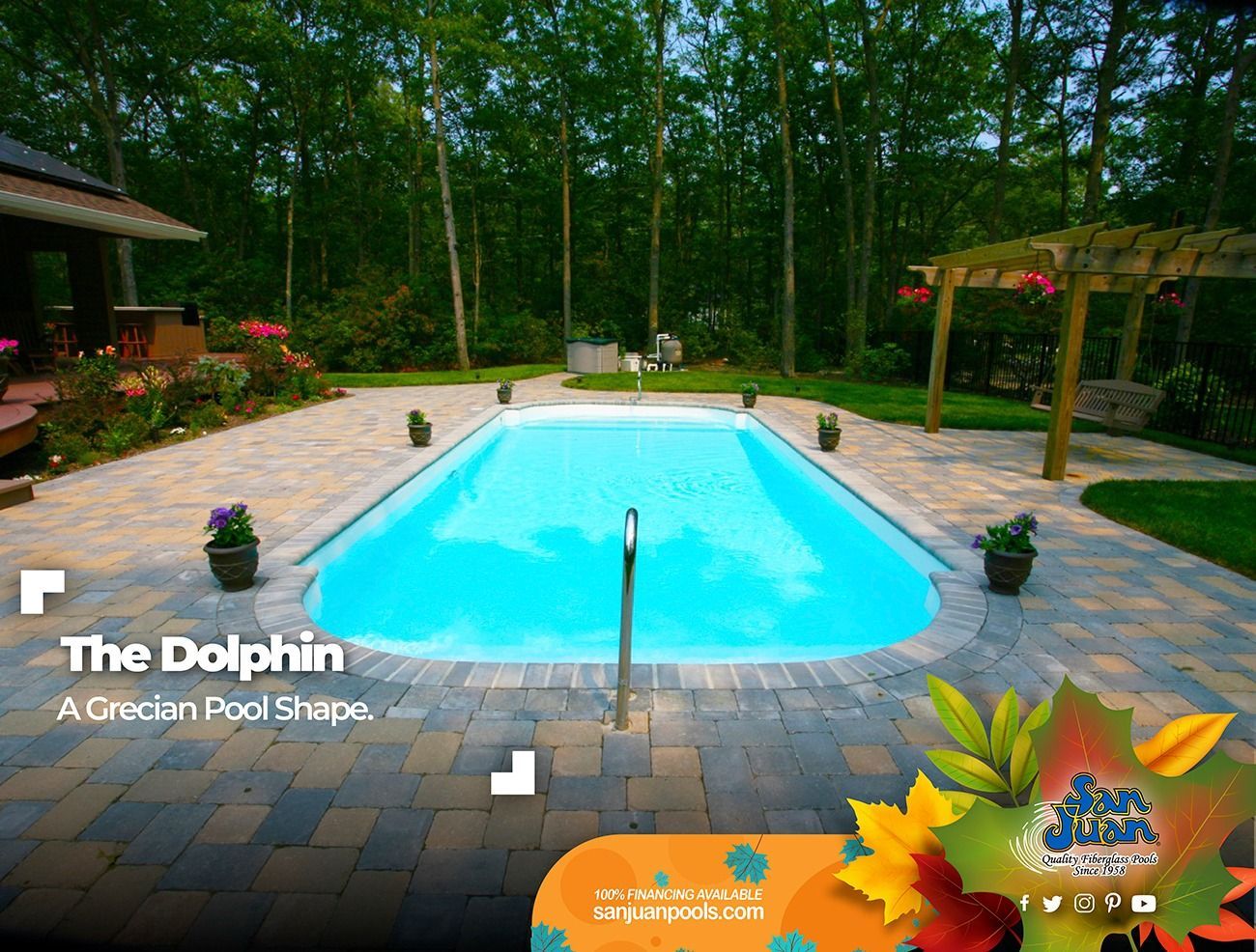 Blue backyard swimming pool with brick patio, trees, and pergola in a wooded setting.