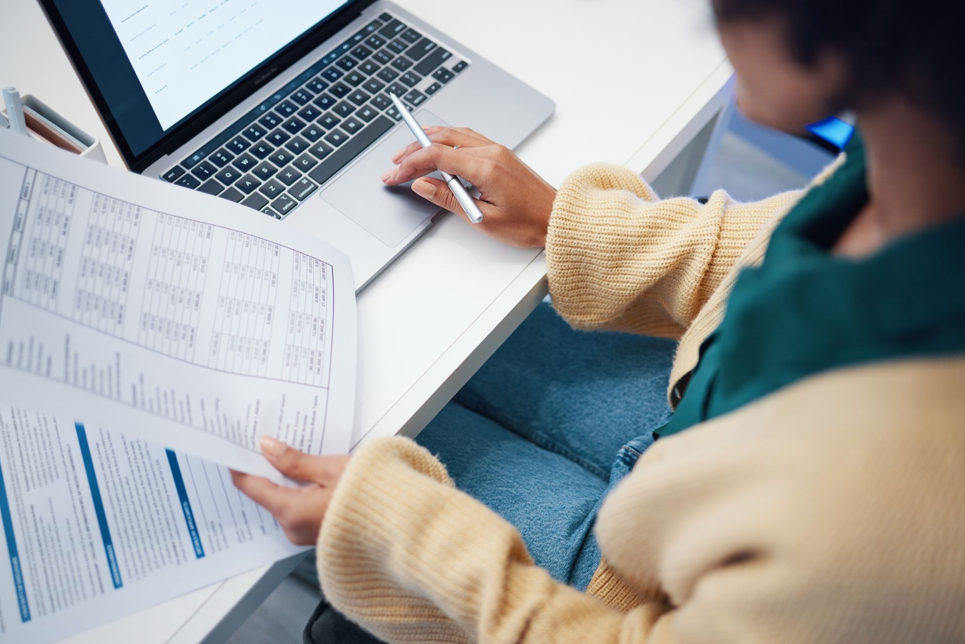 Person reviewing printed charts beside a laptop on a desk