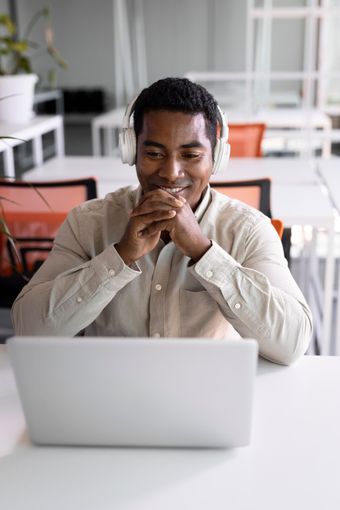 Person smiling behind a laptop in a bright office setting