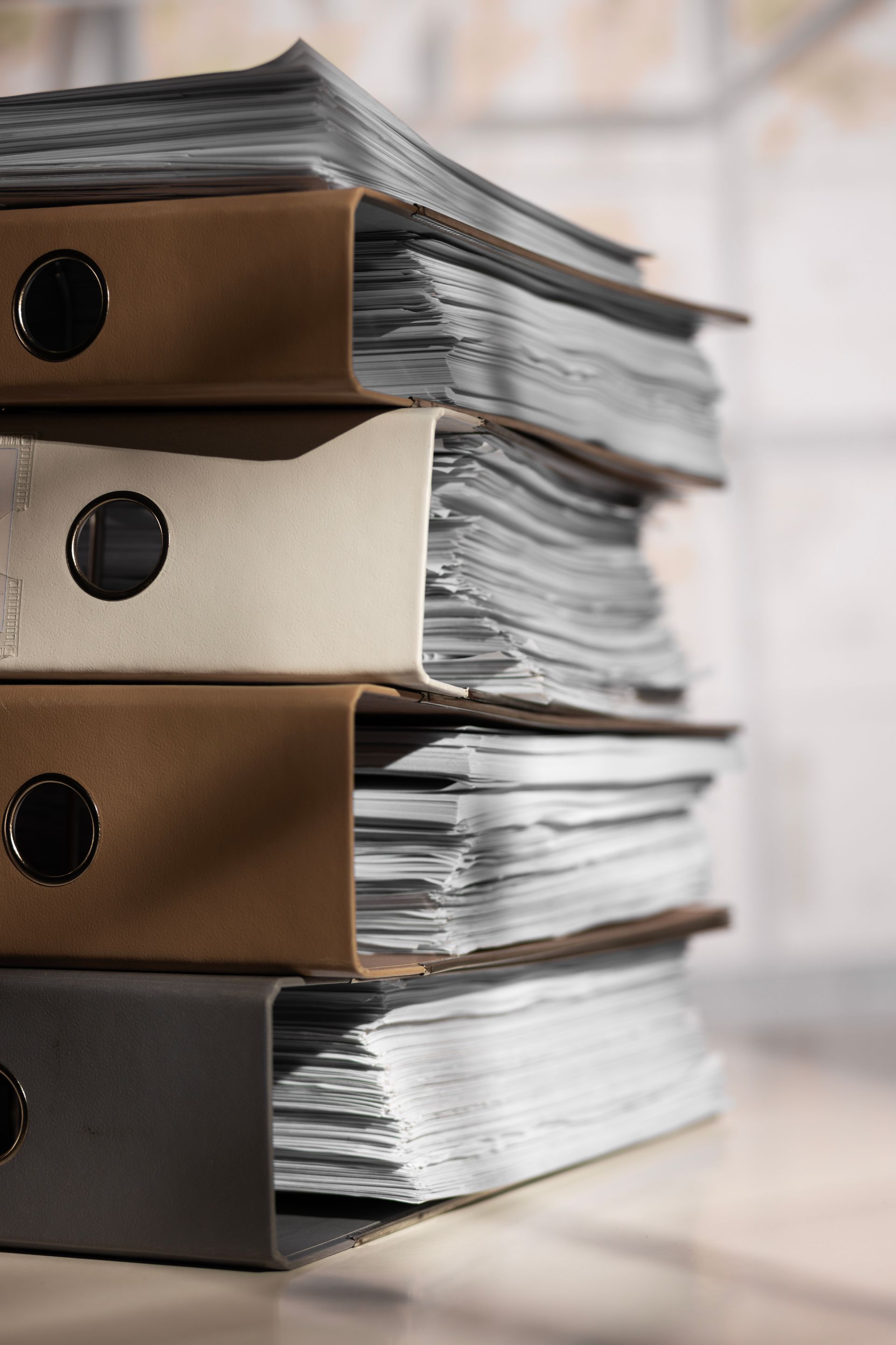 Stacked brown and black file boxes filled with papers on a desk
