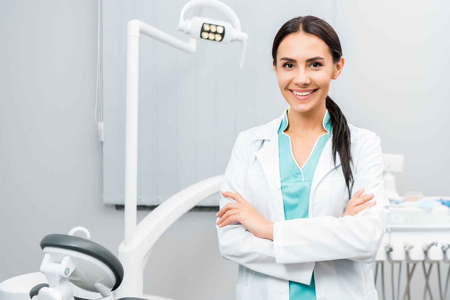 Beautiful dentist standing with crossed arms in dental clinic.