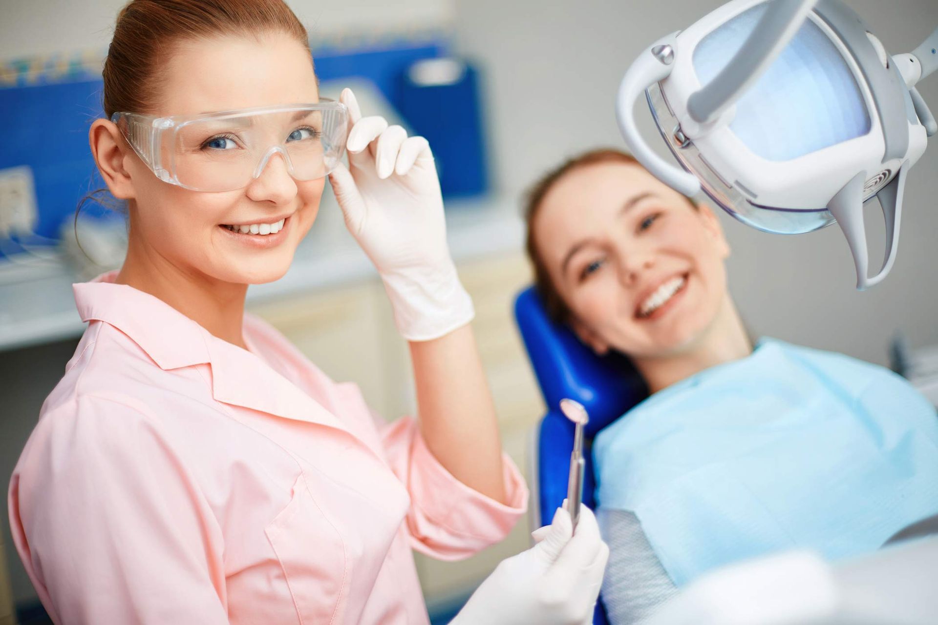 Dentist in uniform looking at camera with her patient on background