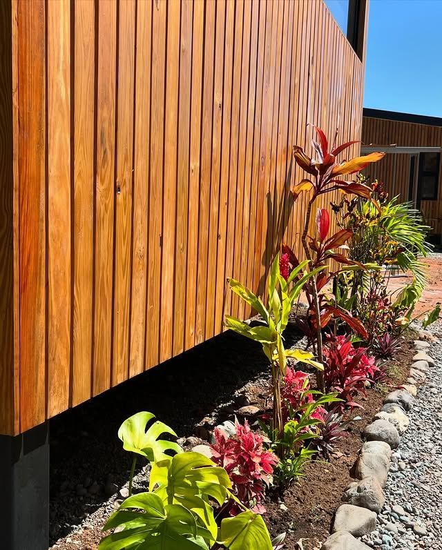 Wooden building facade beside a landscaped garden with colorful tropical plants and stones