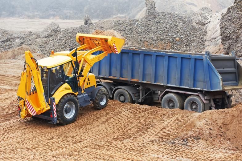 A Yellow Tractor is Loading a Dump Truck With Dirt — Zappala Quarries in Douglas Shire, QLD