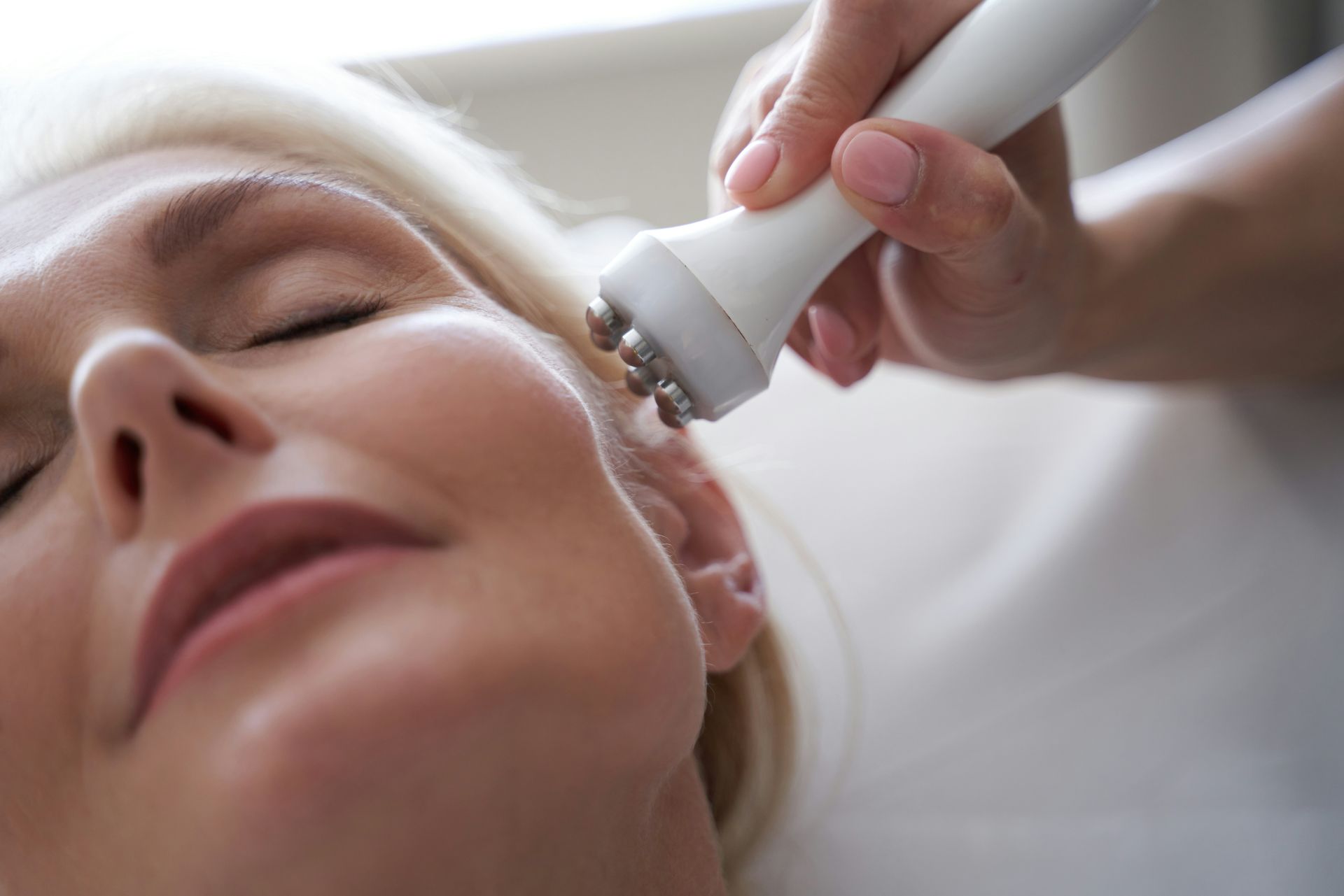 Woman receiving facial treatment with handheld device in a spa setting