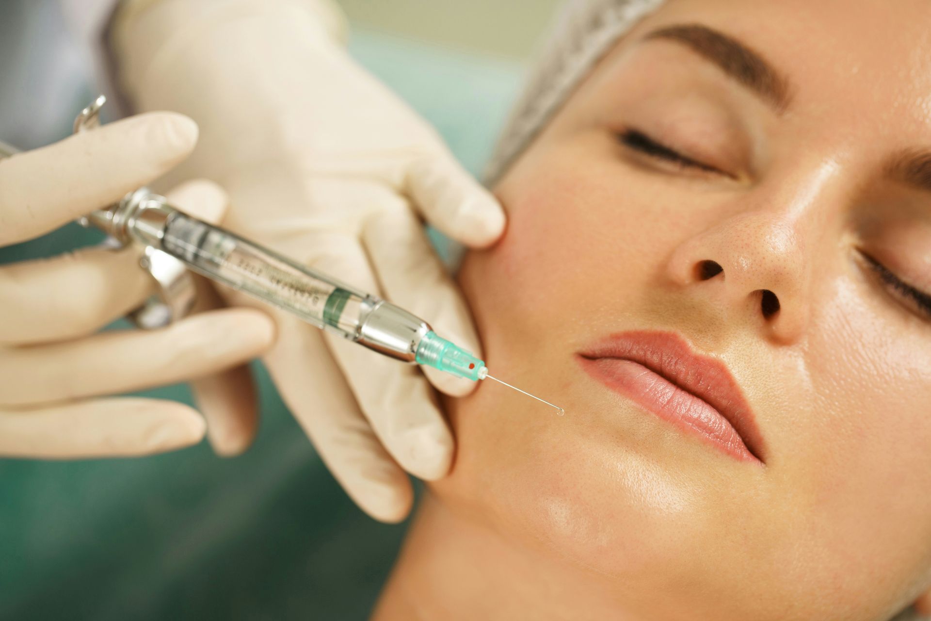 Cosmetic injection being administered to a woman’s cheek by gloved hands