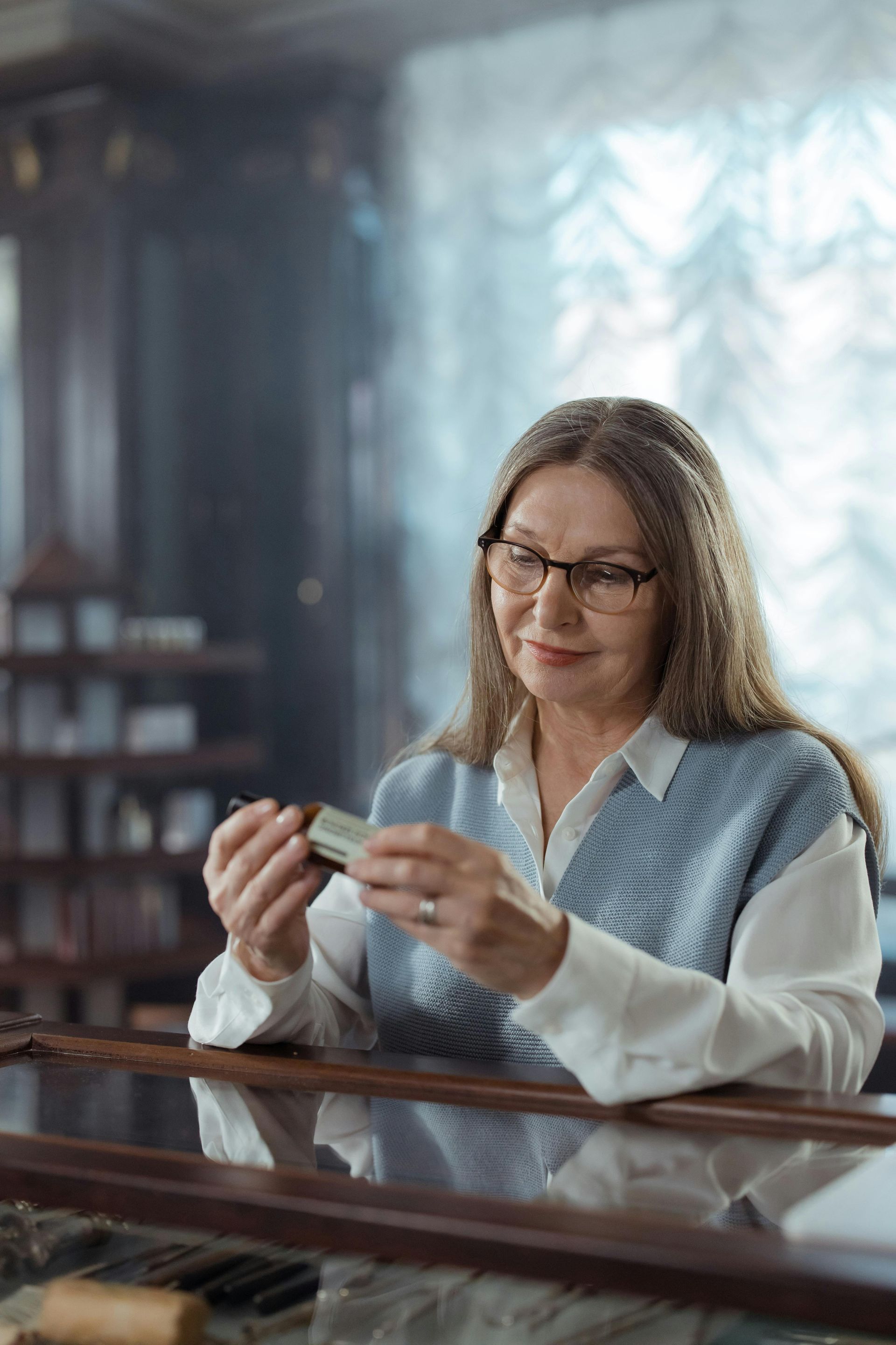 Woman in a blue sweater holding a card at a table in a softly lit room