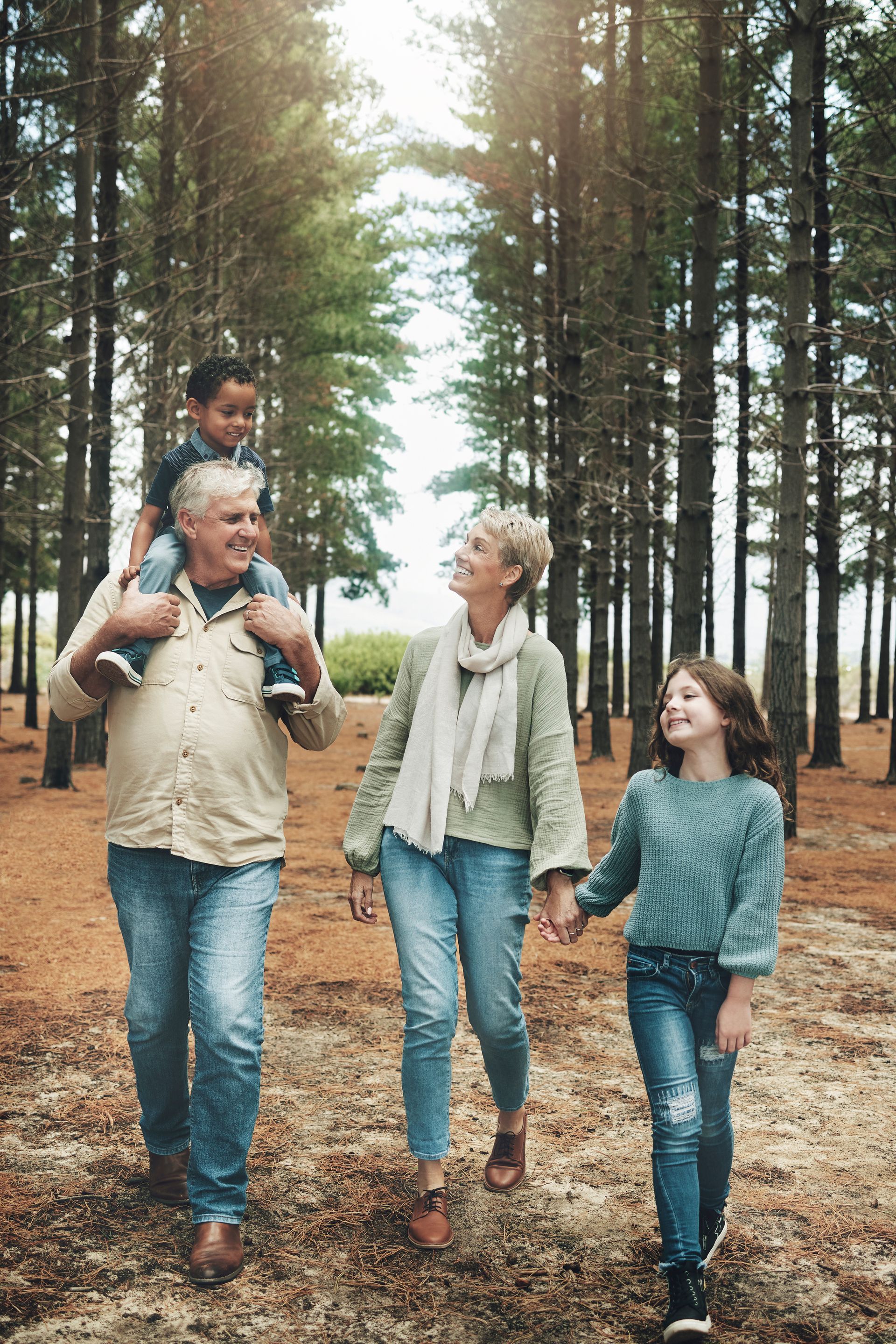A family is walking through a forest holding hands.