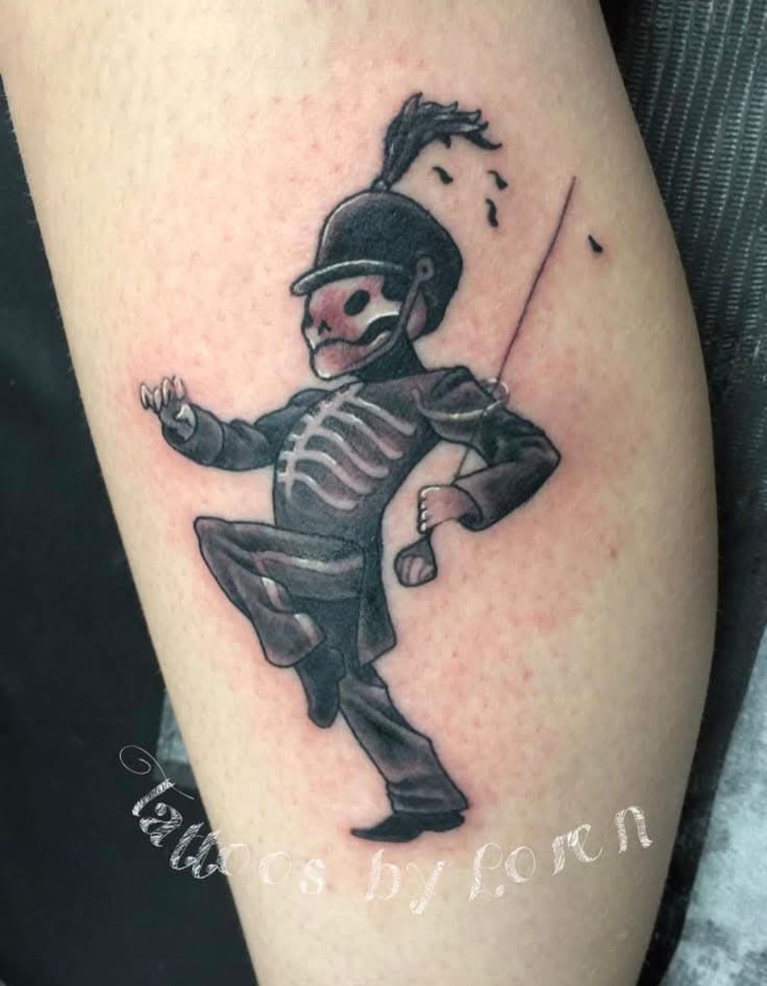 Tattoo of a skeletal marching band member in black uniform on an arm.