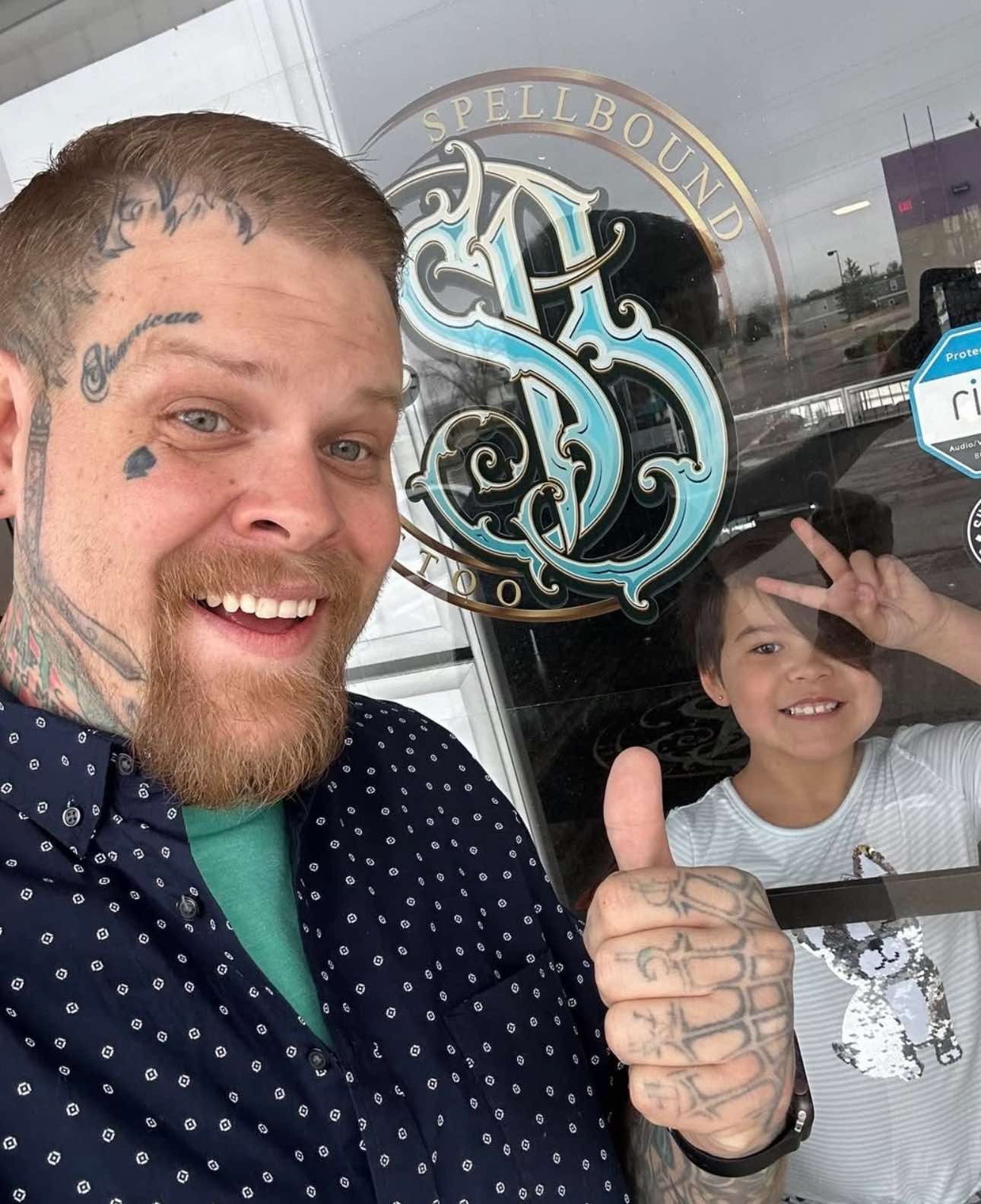 Man and child smiling, giving thumbs-up and peace signs near a storefront with