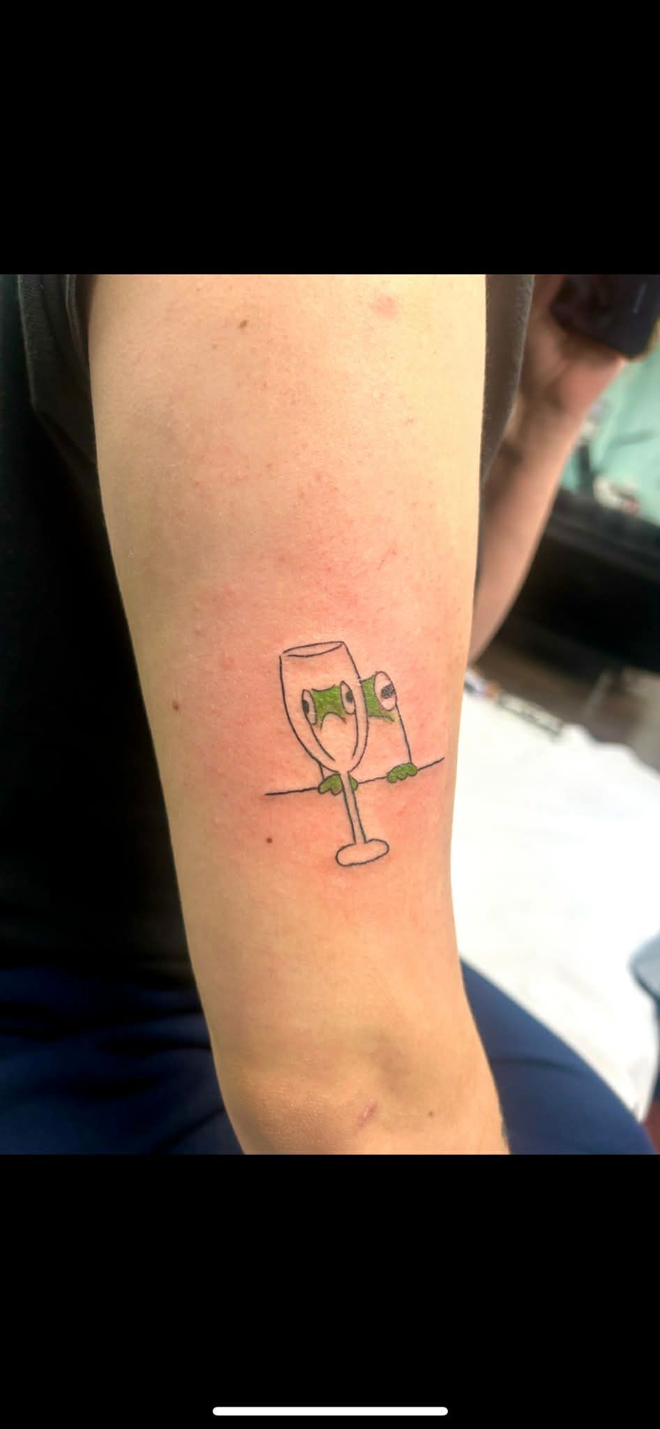 Tattoo of champagne flutes on a person's forearm. One flute has 