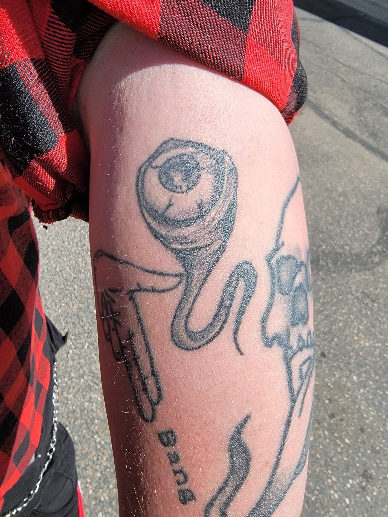 Arm with tattoos; an eyeball, skull, and 