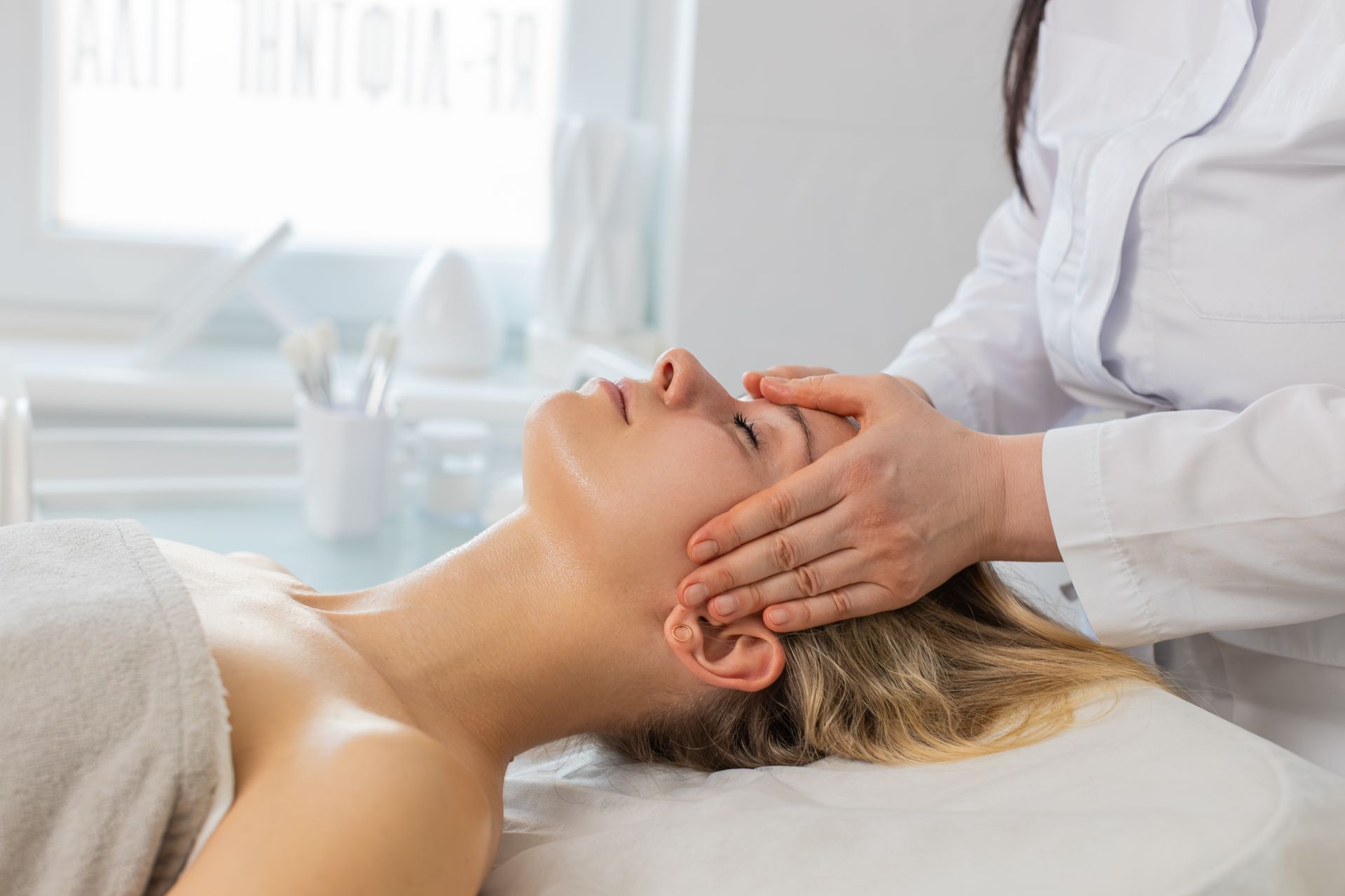 A person lies relaxed on a massage table receiving a back massage, overlaid with decorative white snowflakes and trees. A person lies relaxed on a massage table receiving a back massage, overlaid with decorative white snowflakes and trees.