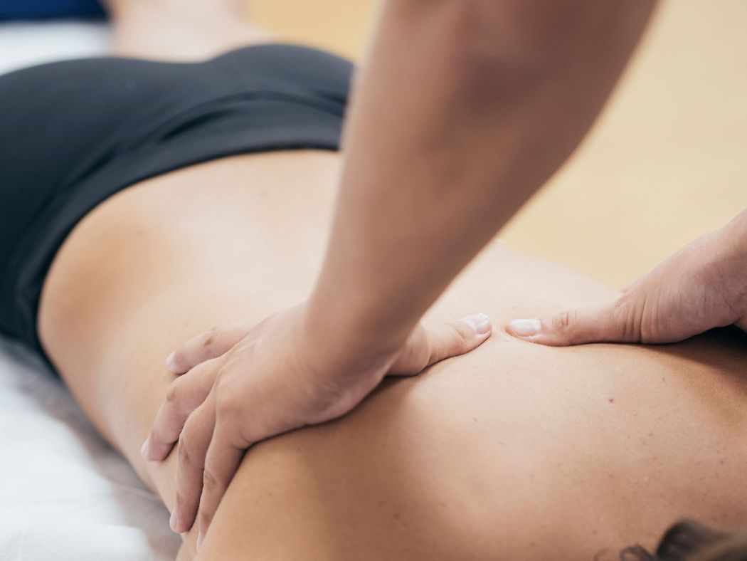A person receiving a massage on their back from a therapist in a clinical setting.