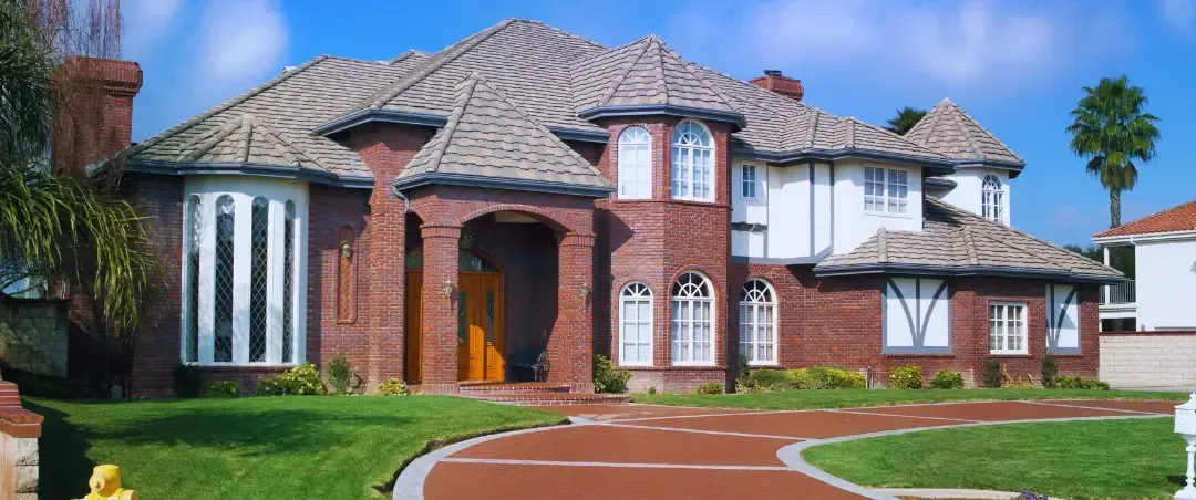 A large brick house with a red driveway and a fire hydrant in front of it.