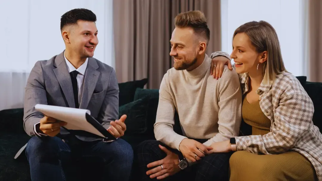 A man is sitting on a couch talking to a couple.