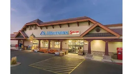 The front of a grocery store with a parking lot in front of it.