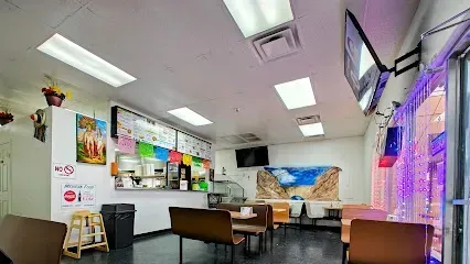 The inside of a restaurant with tables and chairs and a counter.