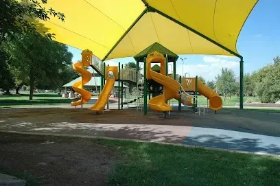 A playground with a yellow umbrella over it