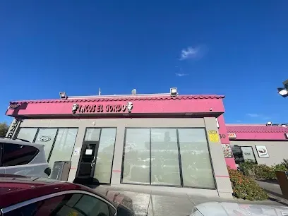 A car is parked in front of a building with a pink roof.