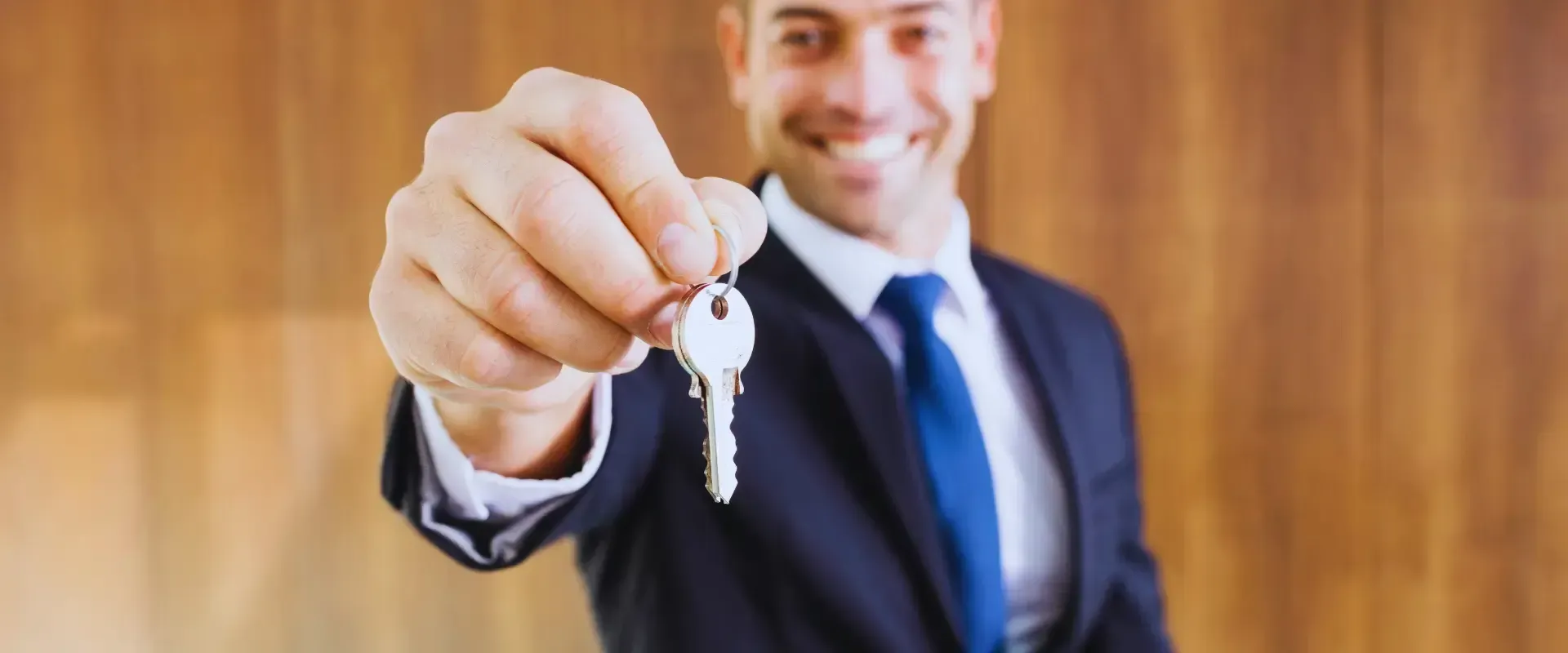 A man in a suit and tie is holding a key in his hand.