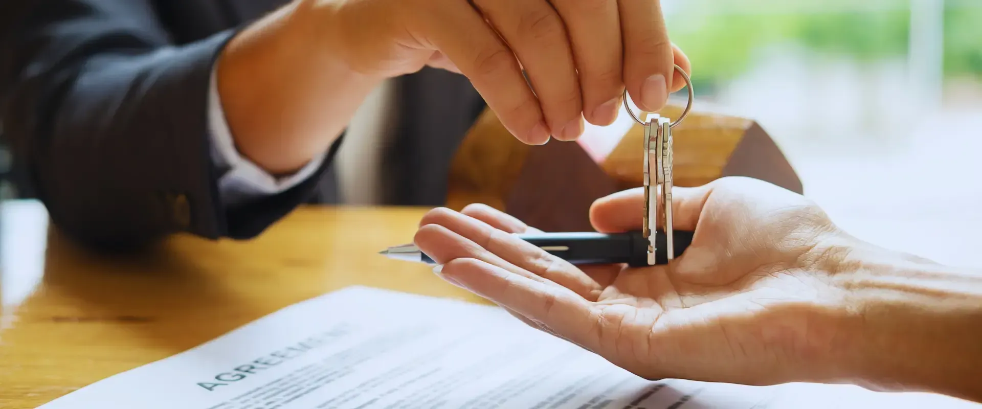 A person is holding a pair of keys over another person 's hand.