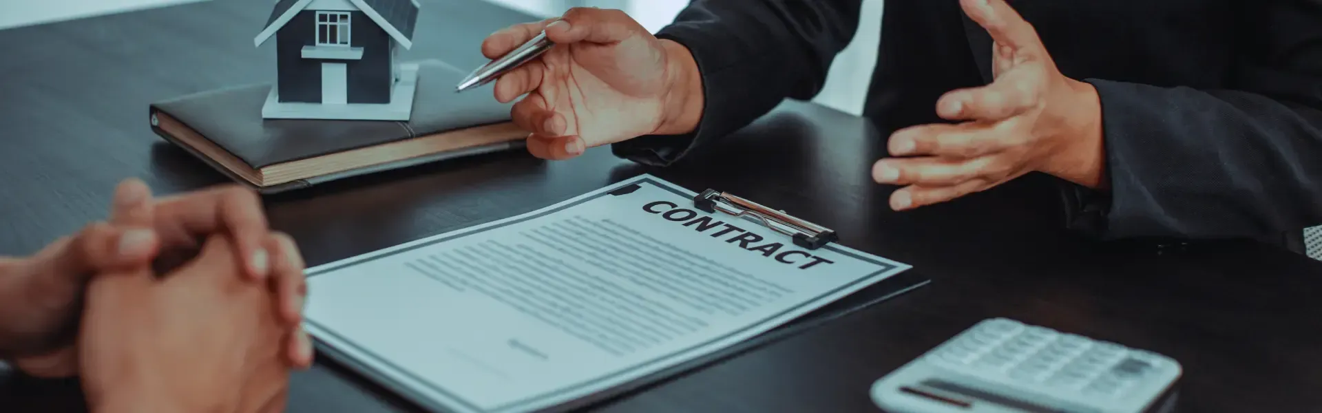A man is sitting at a table talking to a woman while holding a pen.