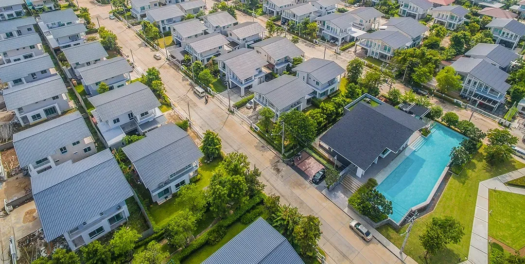 An aerial view of a residential area with lots of houses and a swimming pool.
