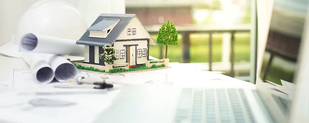 A model house is sitting on top of a laptop computer.