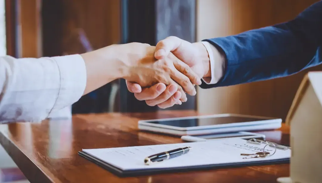 A man and a woman are shaking hands over a table.