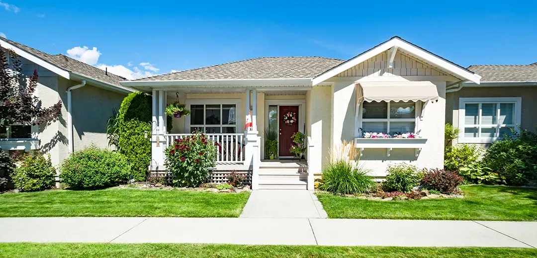 The front of a house with a lush green lawn and a red door.
