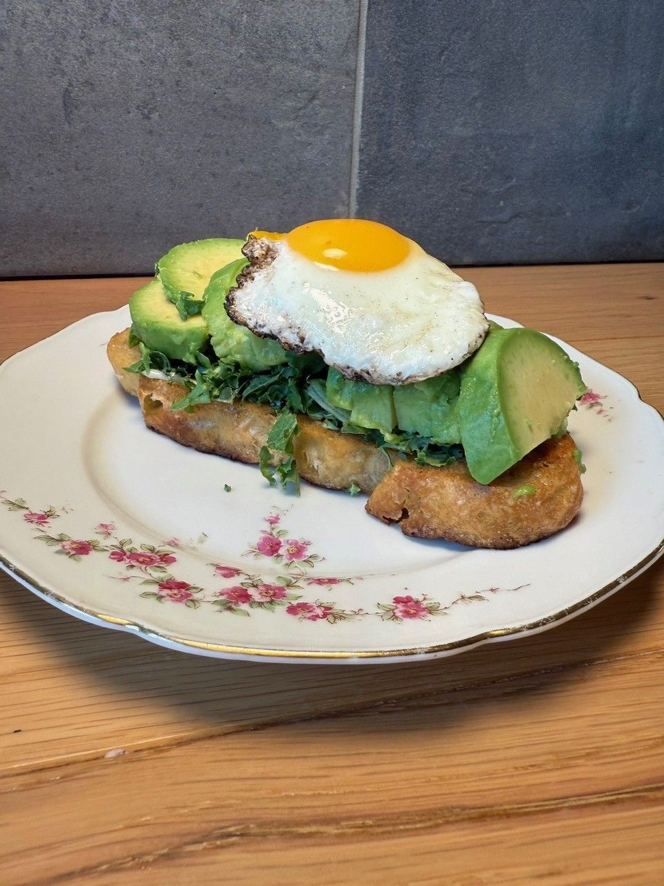 Avocadotoast med spejlæg på en blomstertallerken.