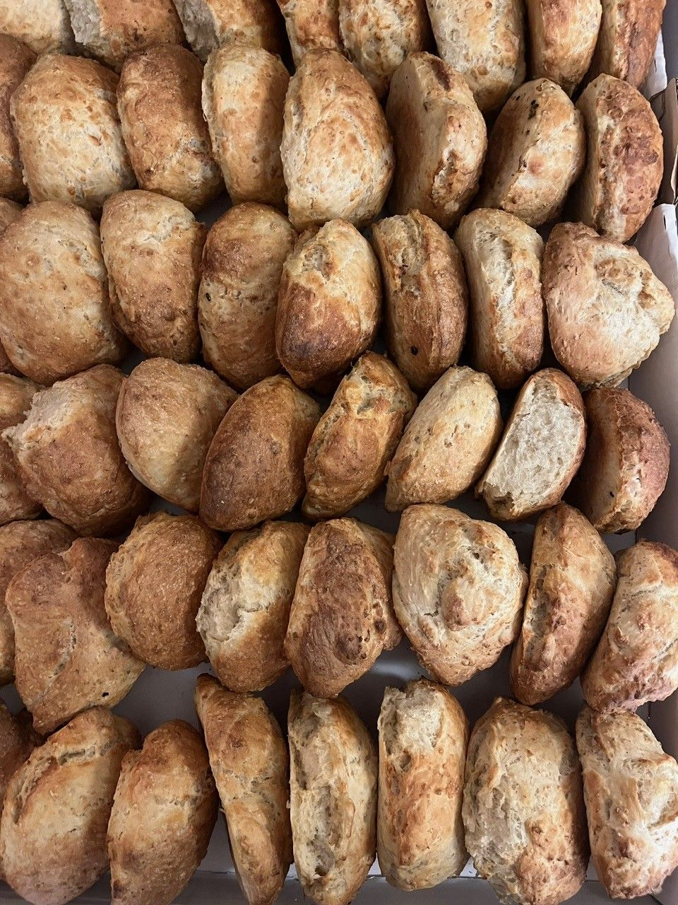 Bakke med små, brune, sprøde rundstykker, muligvis brød.