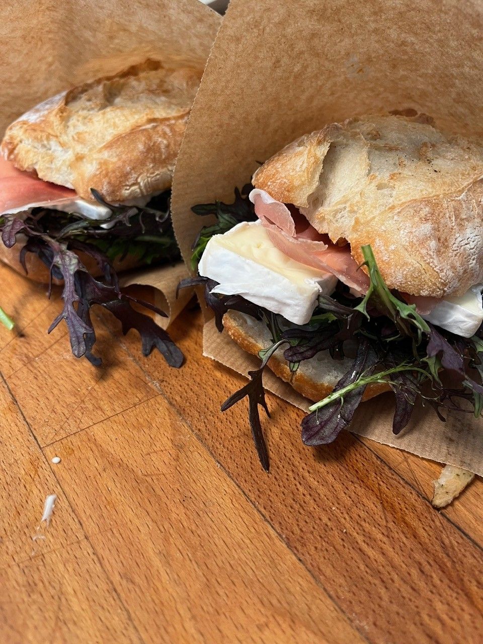 To ristede sandwich med smeltet ost og grøntsager på en træplade