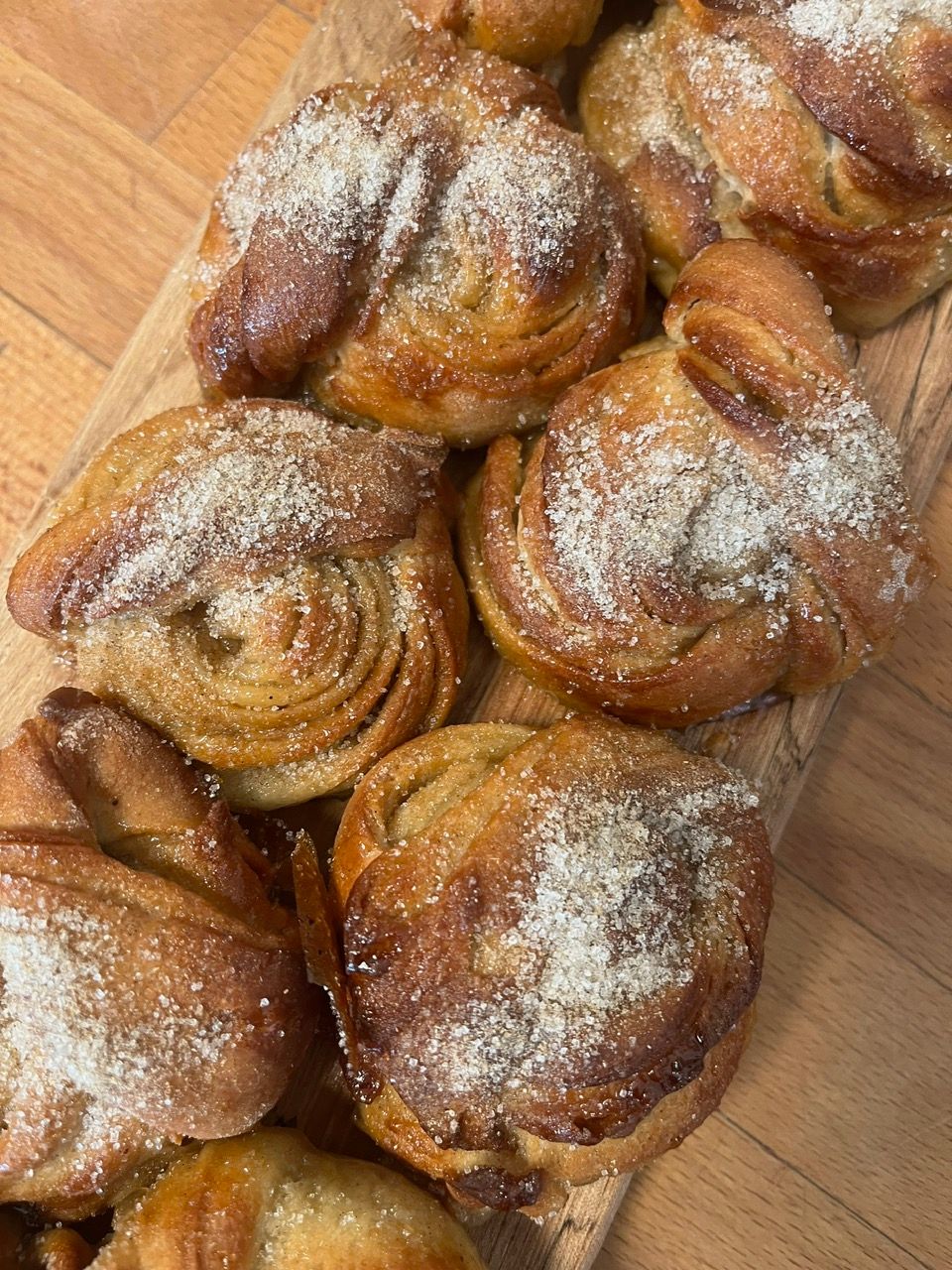 Flere kanelsnurrer dækket af flormelis på et træskærebræt.