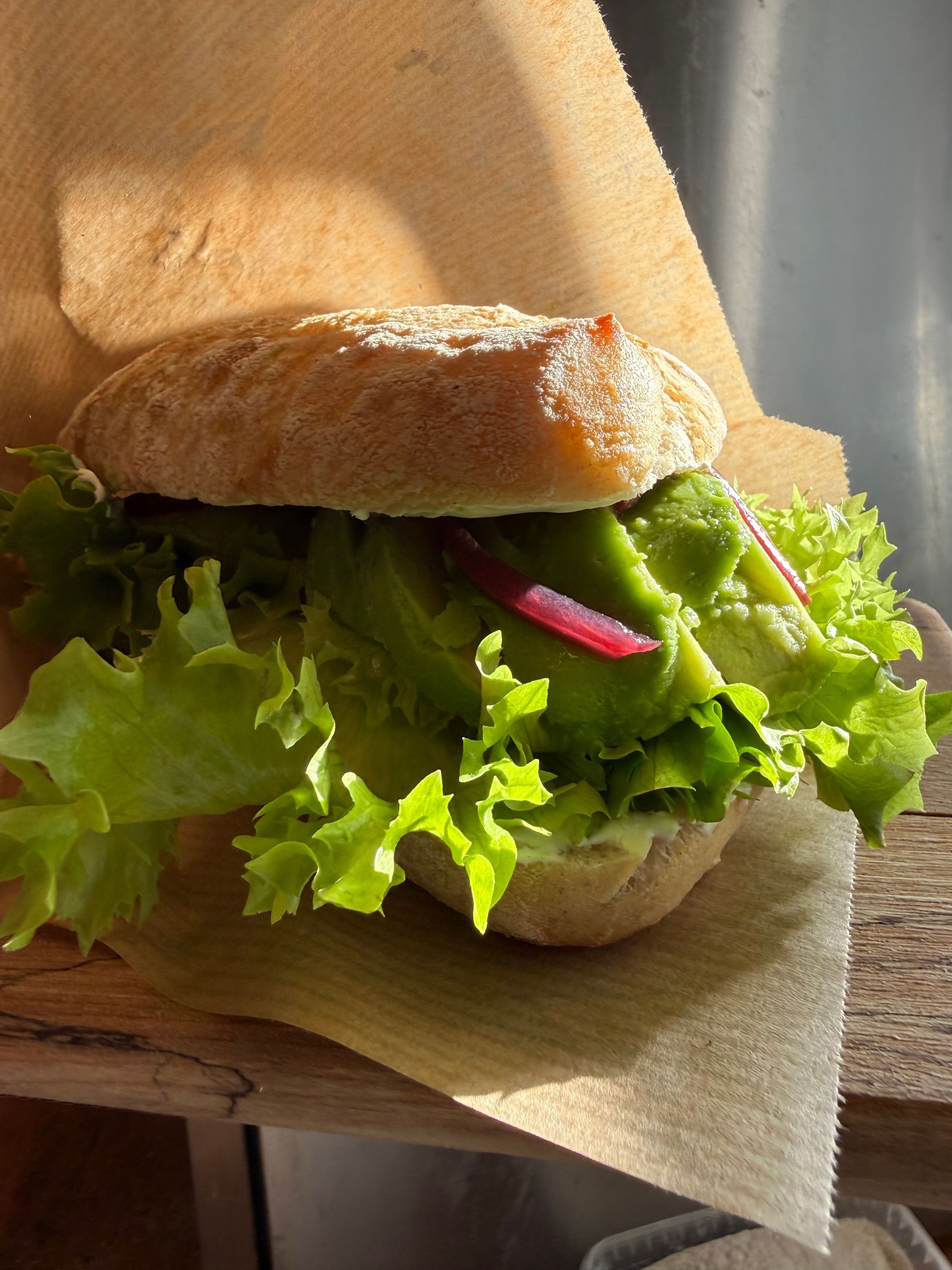 Sandwich med salat og lyserøde løg på en serviet i sollys