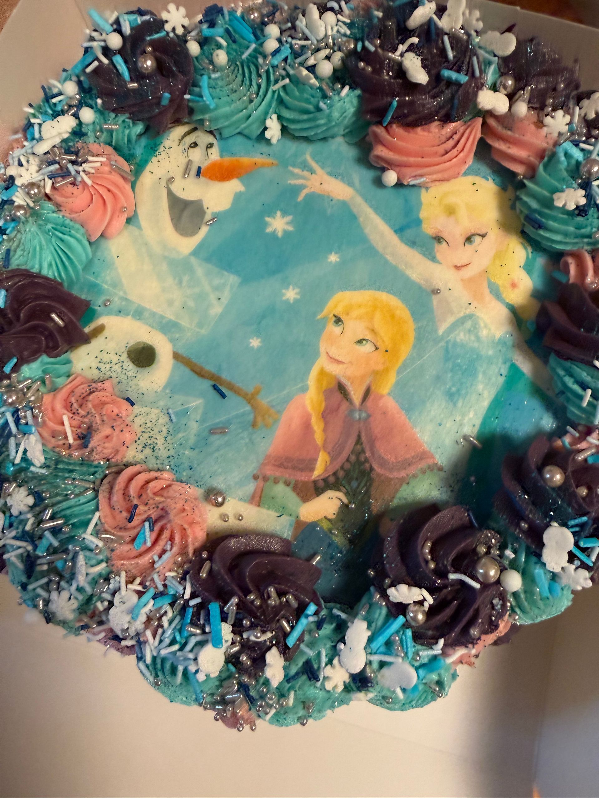 Frost-tema fødselsdagskage med Elsa, Anna, Olaf og blå og lyserød frostingpynt