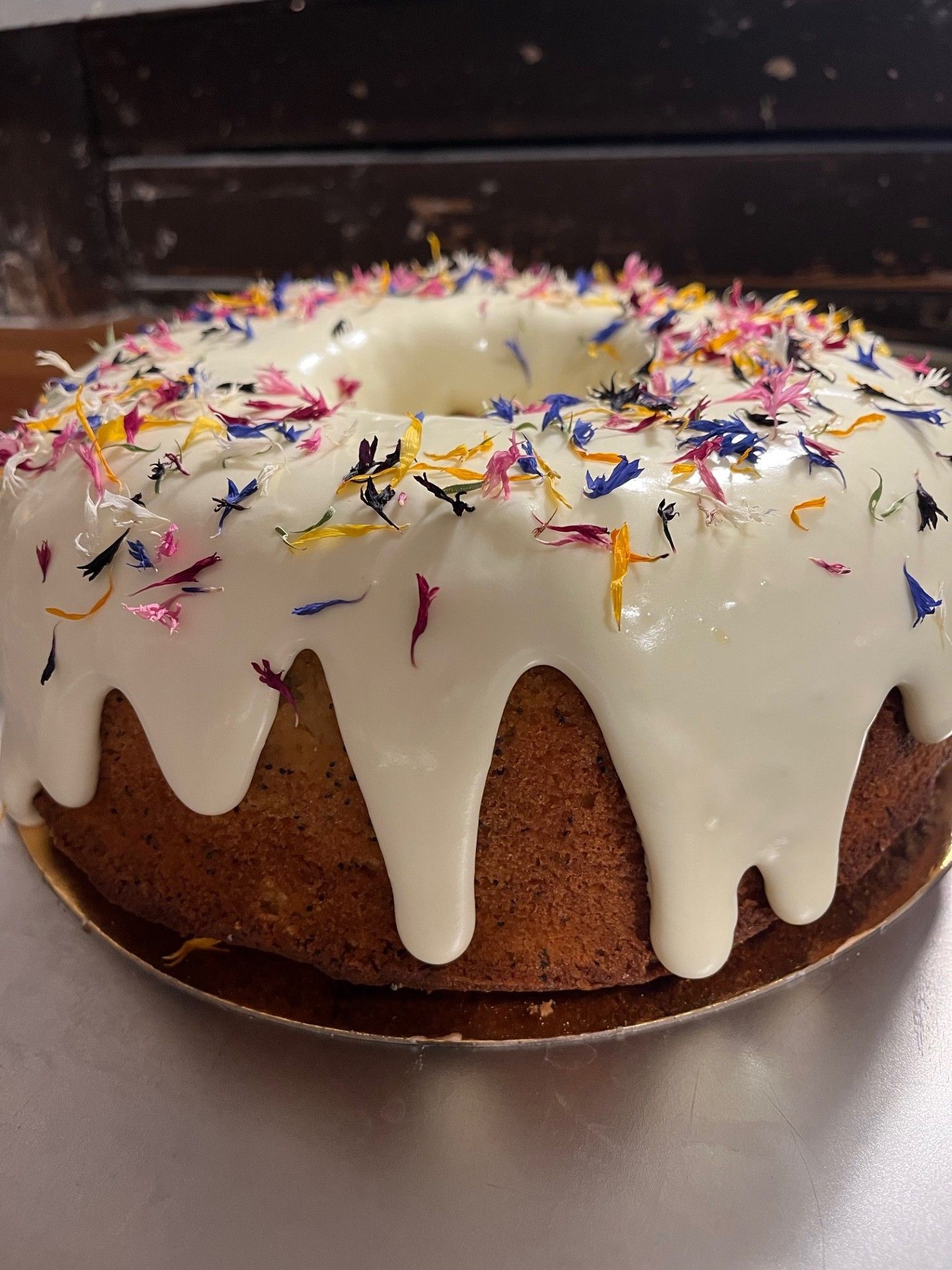 Bundtkage med hvid glasur og farverigt blomsterkrymmel.