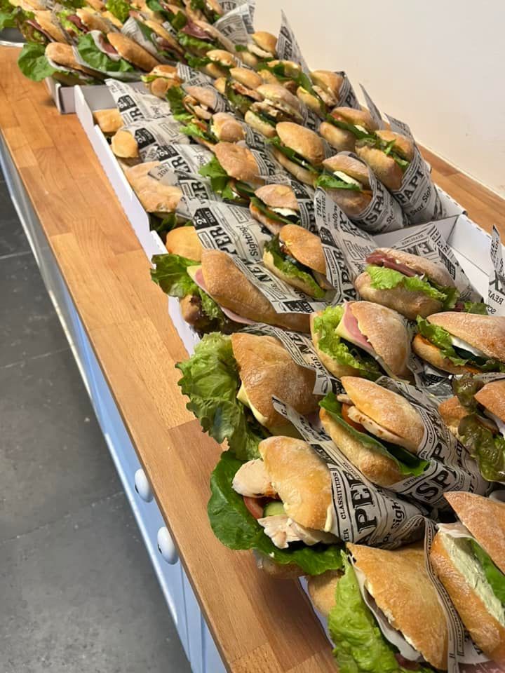 En række sandwich pakket ind i avispapir på et træbord.