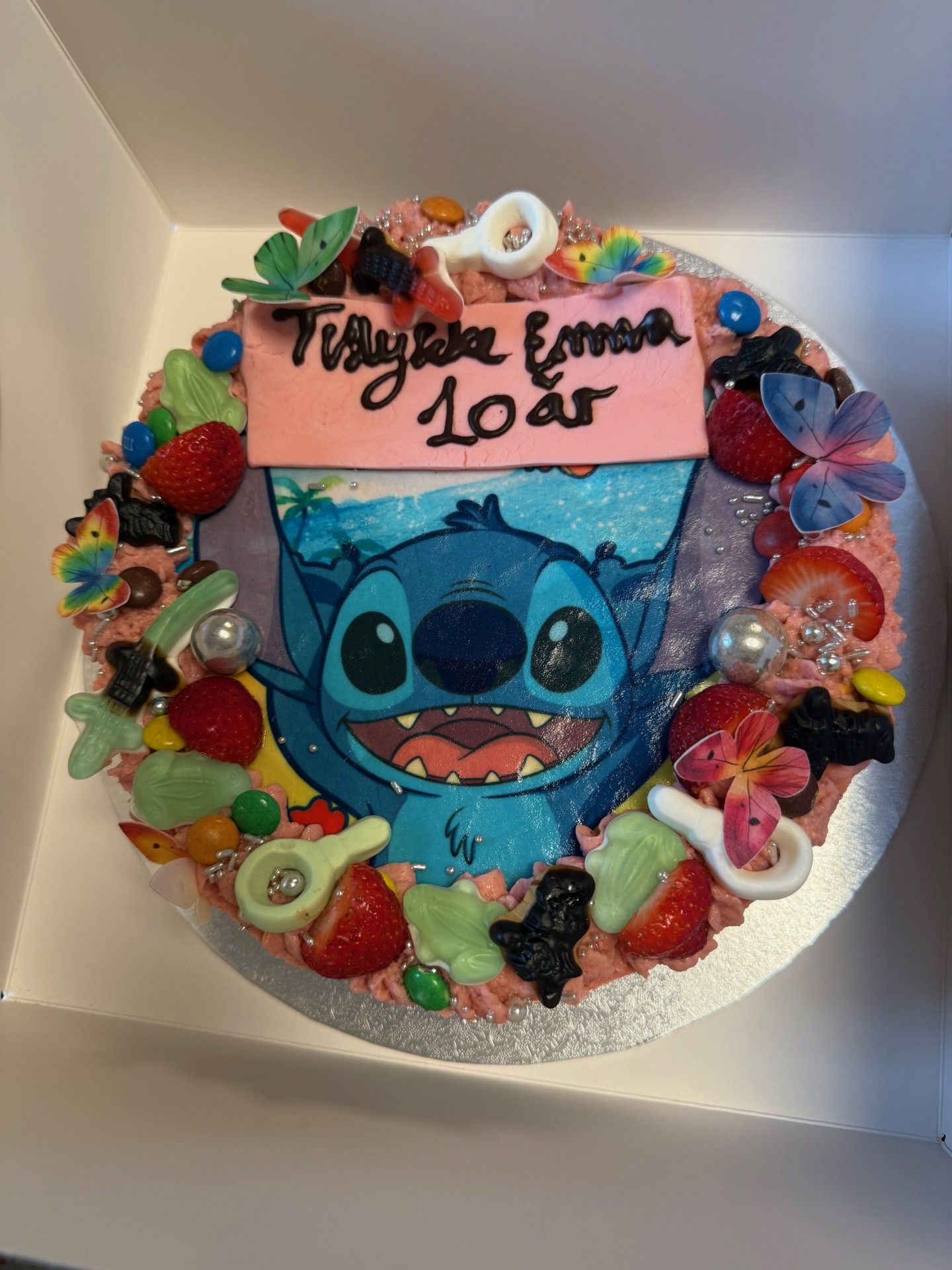 Kage dekoreret med et Stitch-billede, lyserød frosting og slik til en 10-års fødselsdag.