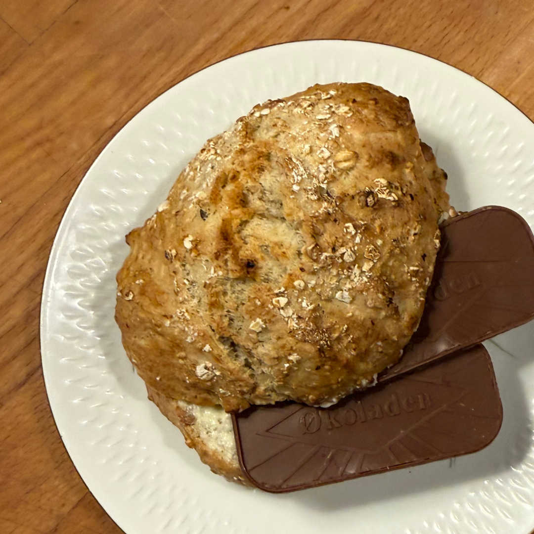 Havregrynsdej på en hvid tallerken med en chokoladebar under.