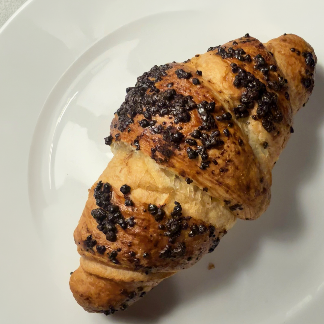 Gyldenbrun croissant toppet med chokoladekrummer på en hvid tallerken